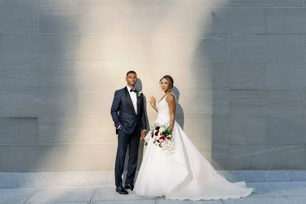 A couple in formal dress against a wall